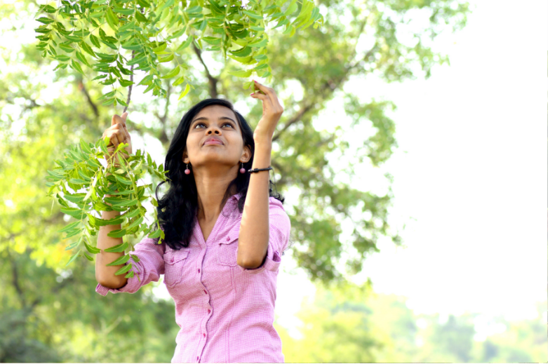 Indische Frau steht unter einem Neem-Baum (Nimba). Der Neem-Baum ist in ganz Indien heimisch, gehört zu fast jedem Dorf